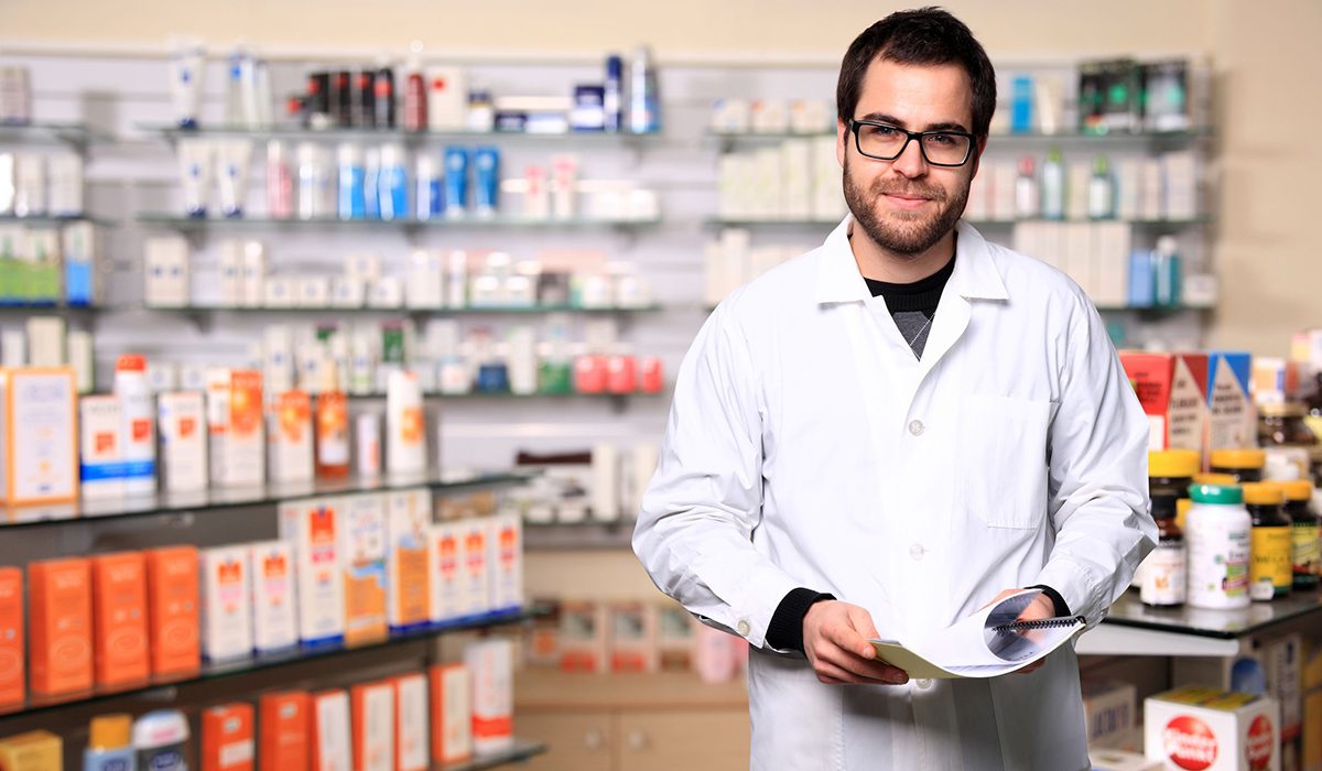 A man in white lab coat holding papers.